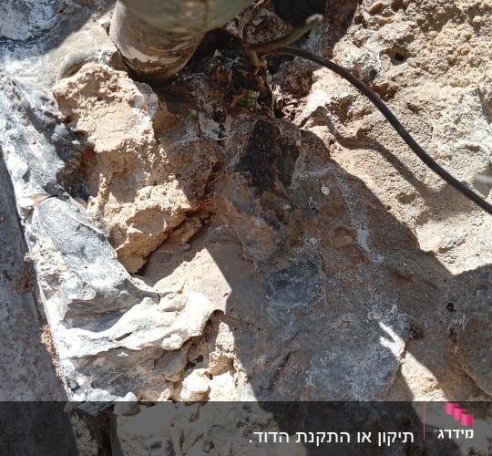 צינור מתכת מחובר לקיר אבן עם חוטים חשמליים
